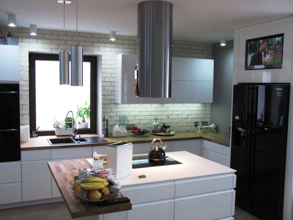 Nowoczesna biała kuchnia z wyspą i cegłą dekoracyjną – KN_EBR